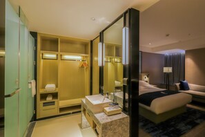 A hotel room with a large bed, a bedside table, a mirror, a wardrobe, and a bathroom with a sink and towel rack. - ECHARM HOTEL（Xi Qiao Shan, Foshan） (Foshan)