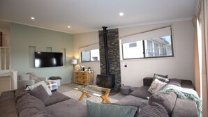 A living room with a fireplace, sofas, a coffee table, and a TV. - Boronia - 7/30 Nettin Circuit (Jindabyne)