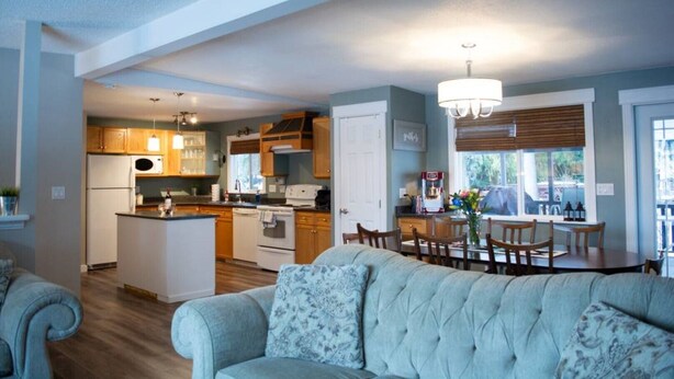 A modern kitchen with wooden cabinets, a dining area with a table and chairs, and a living room with a sofa.