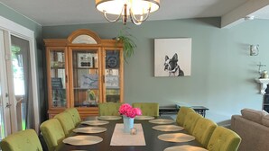 A dining room with a dark wooden table, green upholstered chairs, and a chandelier.
