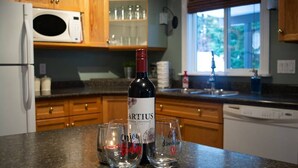 A kitchen with wooden cabinets, a microwave, and a wine bottle on the counter.