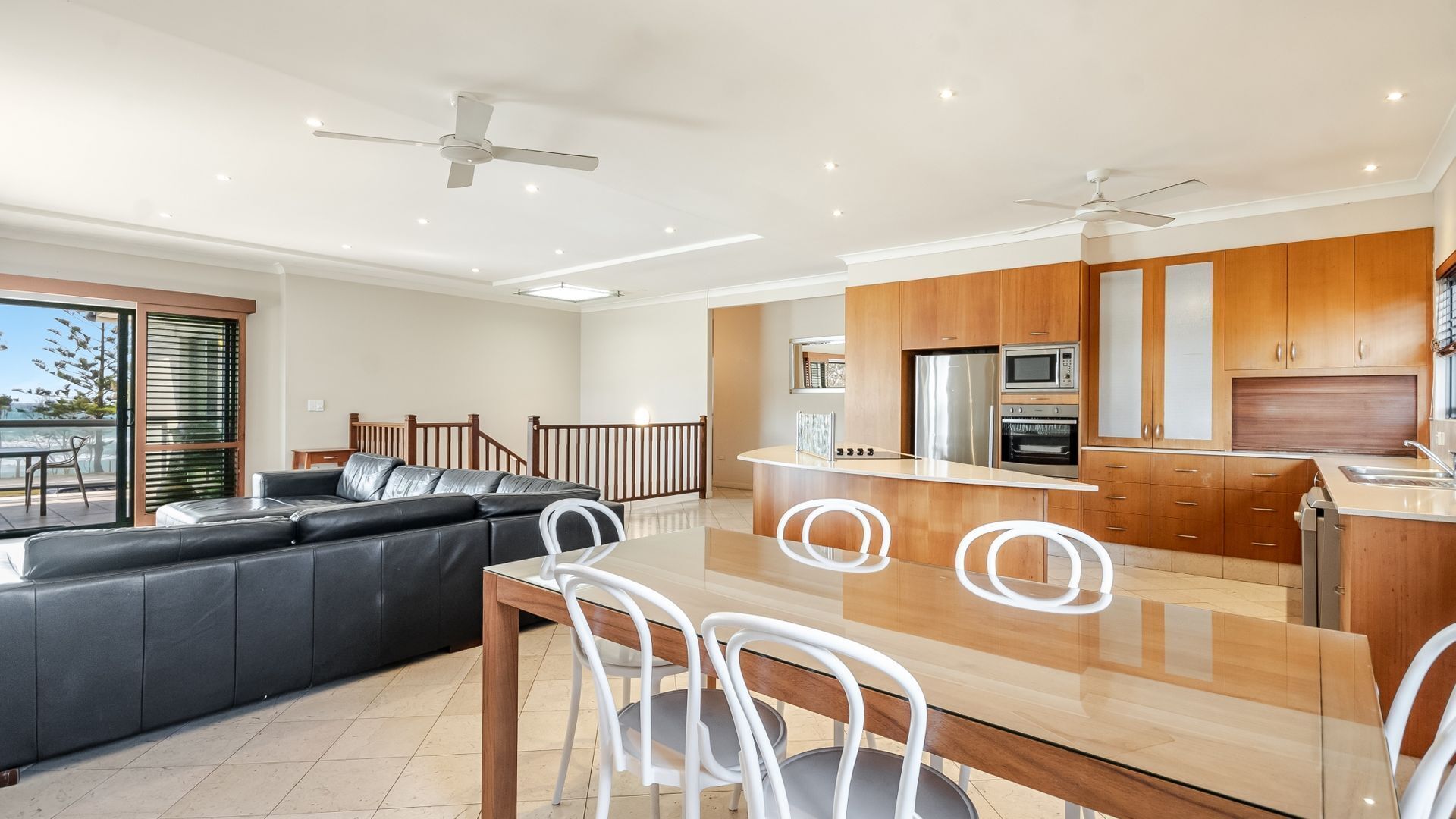 A modern kitchen with wooden cabinets, a central island, and built-in appliances.