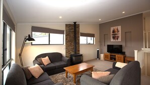 A modern living room with a fireplace, sofas, a coffee table, and a TV.