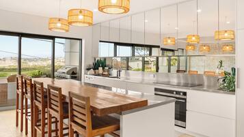 A modern kitchen with a large island, white cabinetry, and a view of the outdoors.