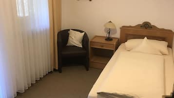 A hotel room with a bed, a chair, a nightstand, a lamp, and a picture on the wall.