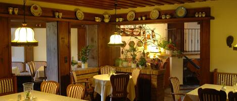 Un acogedor interior de restaurante con vigas de madera, varias mesas y sillas.