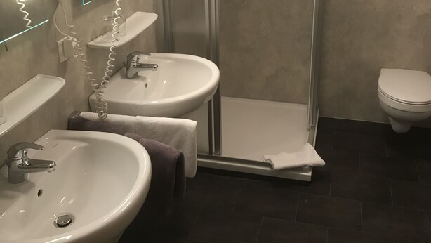 A bathroom with two sinks, a shower, and a toilet. - Landhaus Preißinger (Warmensteinach)