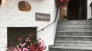 A white building with a sign reading "Eingang" and a wooden plaque above a door. - Landhaus Preißinger (Warmensteinach)