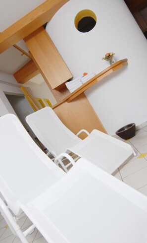 A modern bathroom with white fixtures, a wooden vanity, and a small shelf with flowers. - Hotel Wiesend (Kulmain)