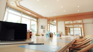 Uma sala de conferências com um laptop, uma caneta e um caderno sobre a mesa.