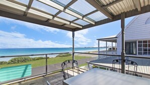 Área externa coberta com vista para o oceano, uma piscina e um edifício com varanda.
