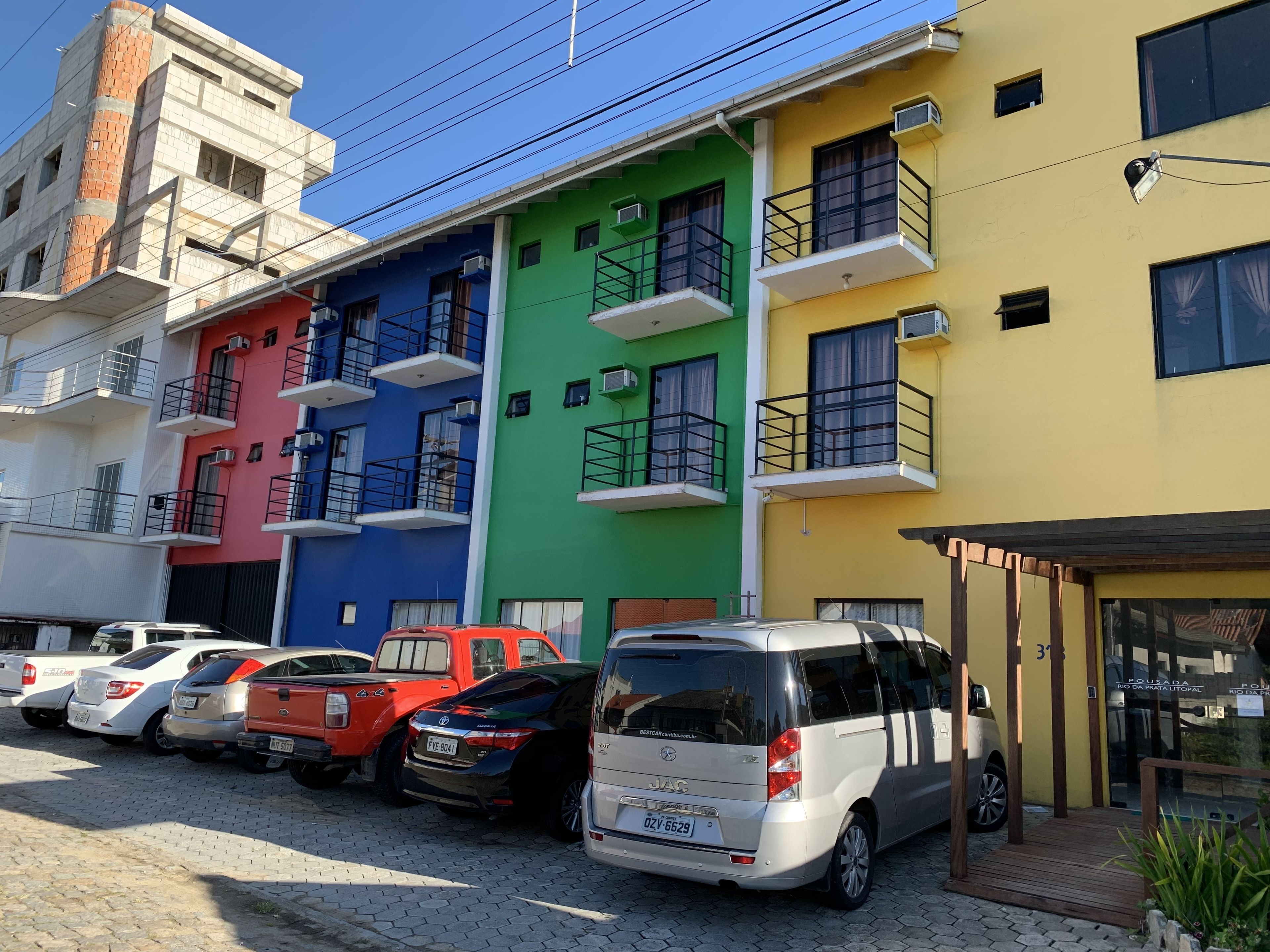 A multi-story building with colorful facades and a parking area with various cars.