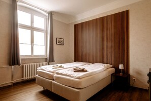 A room with a bed, a window with curtains, a radiator, and a wooden panel wall.