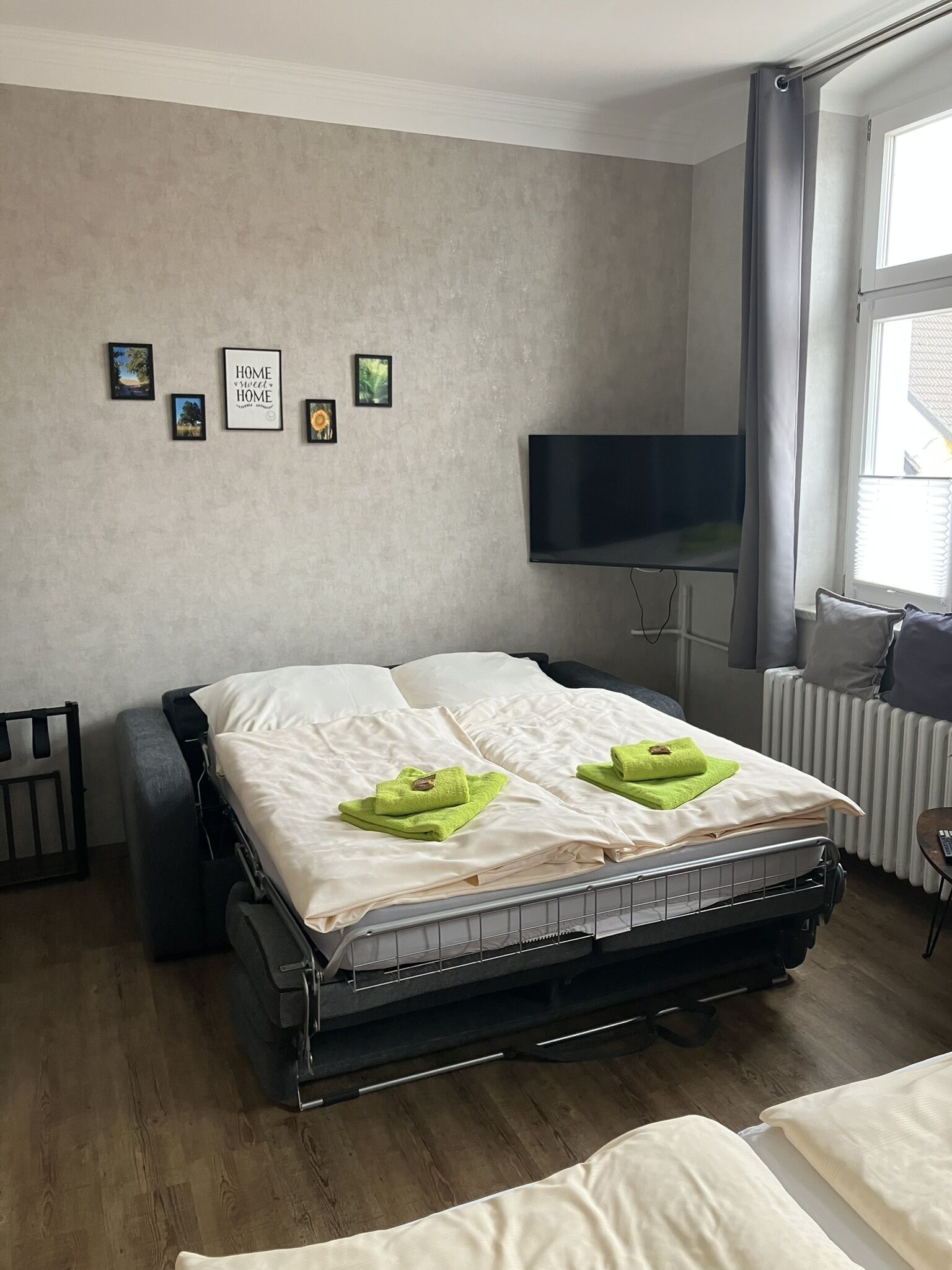 Un dormitorio moderno con cama, televisor y ventana con cortinas.