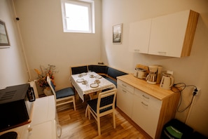 A compact kitchen with a dining table, chairs, a coffee maker, and a microwave. - Hotel Ratsstuben Kalbe (Kalbe)