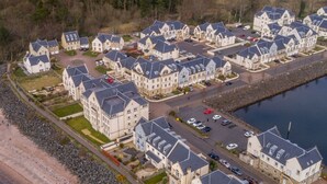 A residential area with multiple two-story houses featuring pitched roofs and a central parking area. - Marina View Apartment (Inverkip)