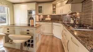 A modern kitchen with white cabinetry, a granite countertop, and a built-in stove. - Marina View Apartment (Inverkip)