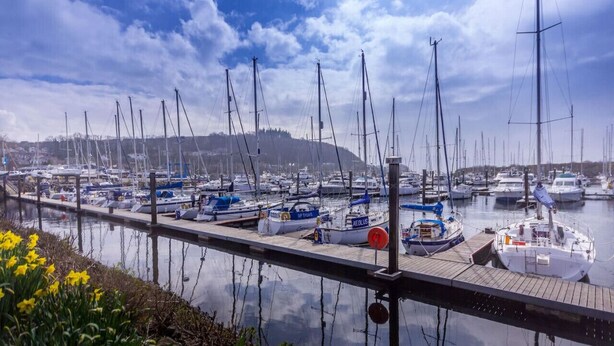 A marina with multiple boats docked along a wooden pier. - Marina View Apartment (Inverkip)