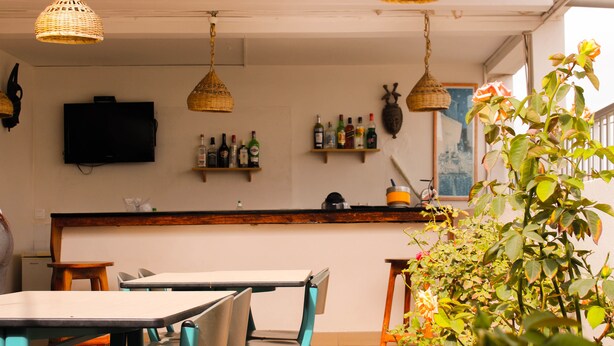A restaurant with tables and chairs, a counter with bottles, and hanging lights. - Maison D'hote O Panoramic (Dakar)