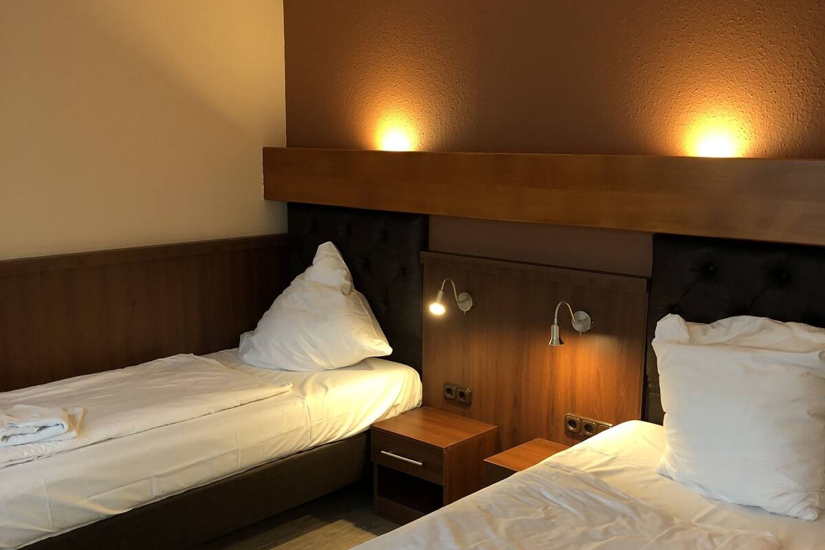 Une chambre d’hôtel avec deux lits, des têtes de lit en bois et des lampes de chevet.