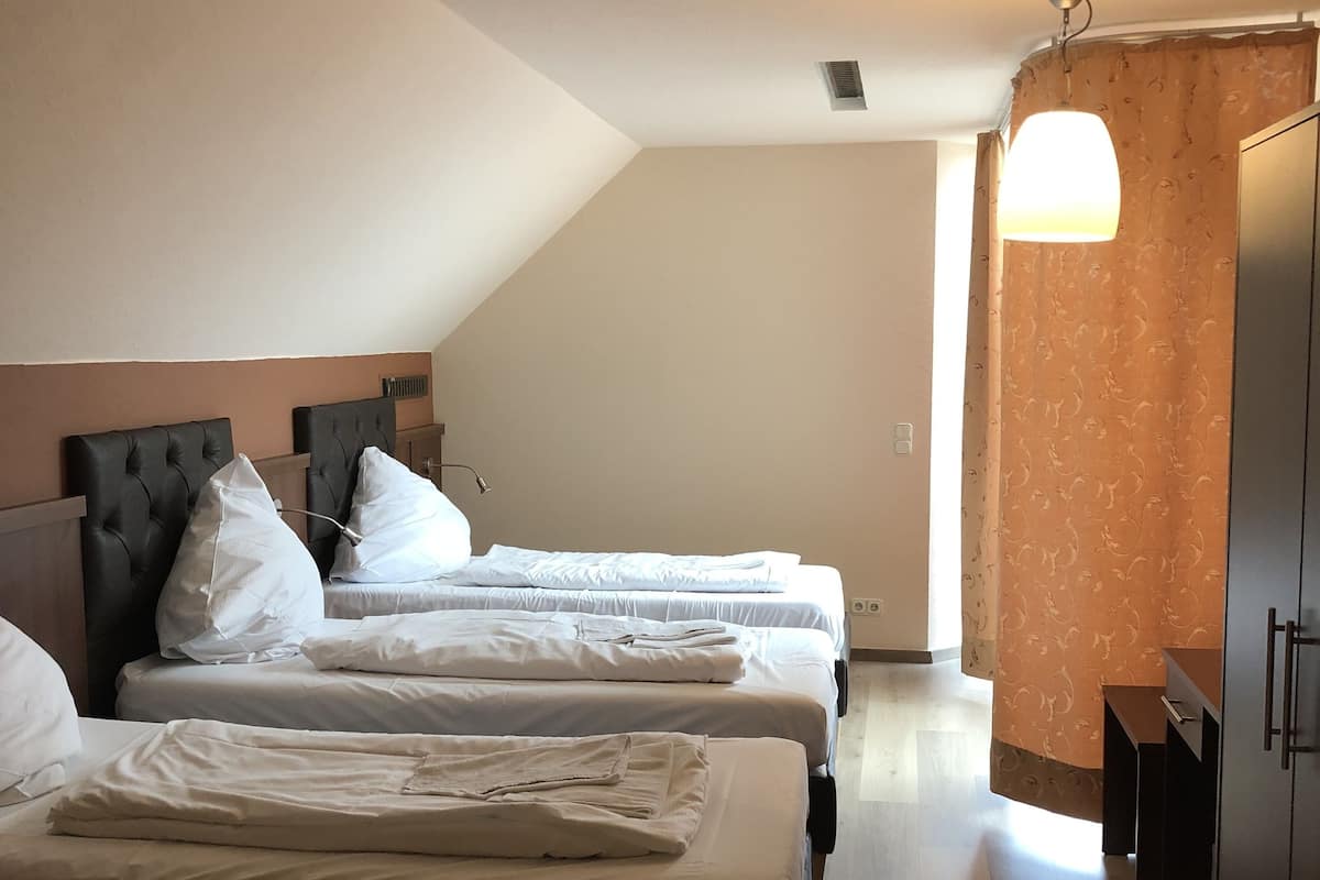 Une chambre d’hôtel avec deux lits, une armoire et une fenêtre avec des rideaux.