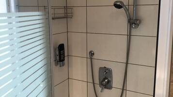 A shower area with a handheld showerhead, a wall-mounted faucet, and a control panel.