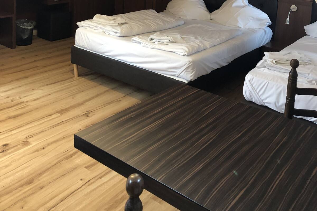 Une chambre avec un grand lit, un plus petit lit, une télévision et une armoire.