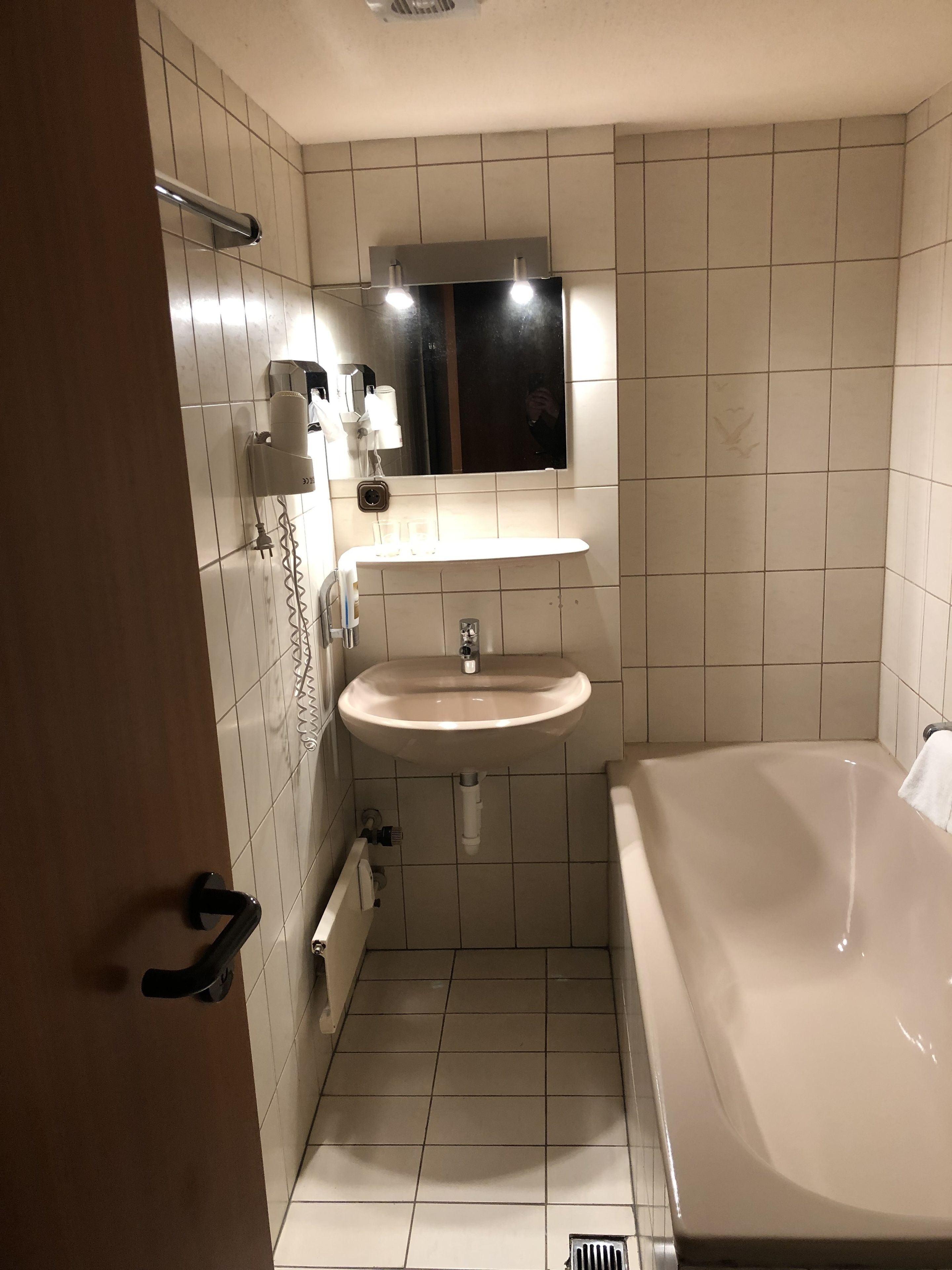 A bathroom with a sink, mirror, and bathtub.