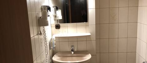A bathroom with a sink, mirror, and bathtub.