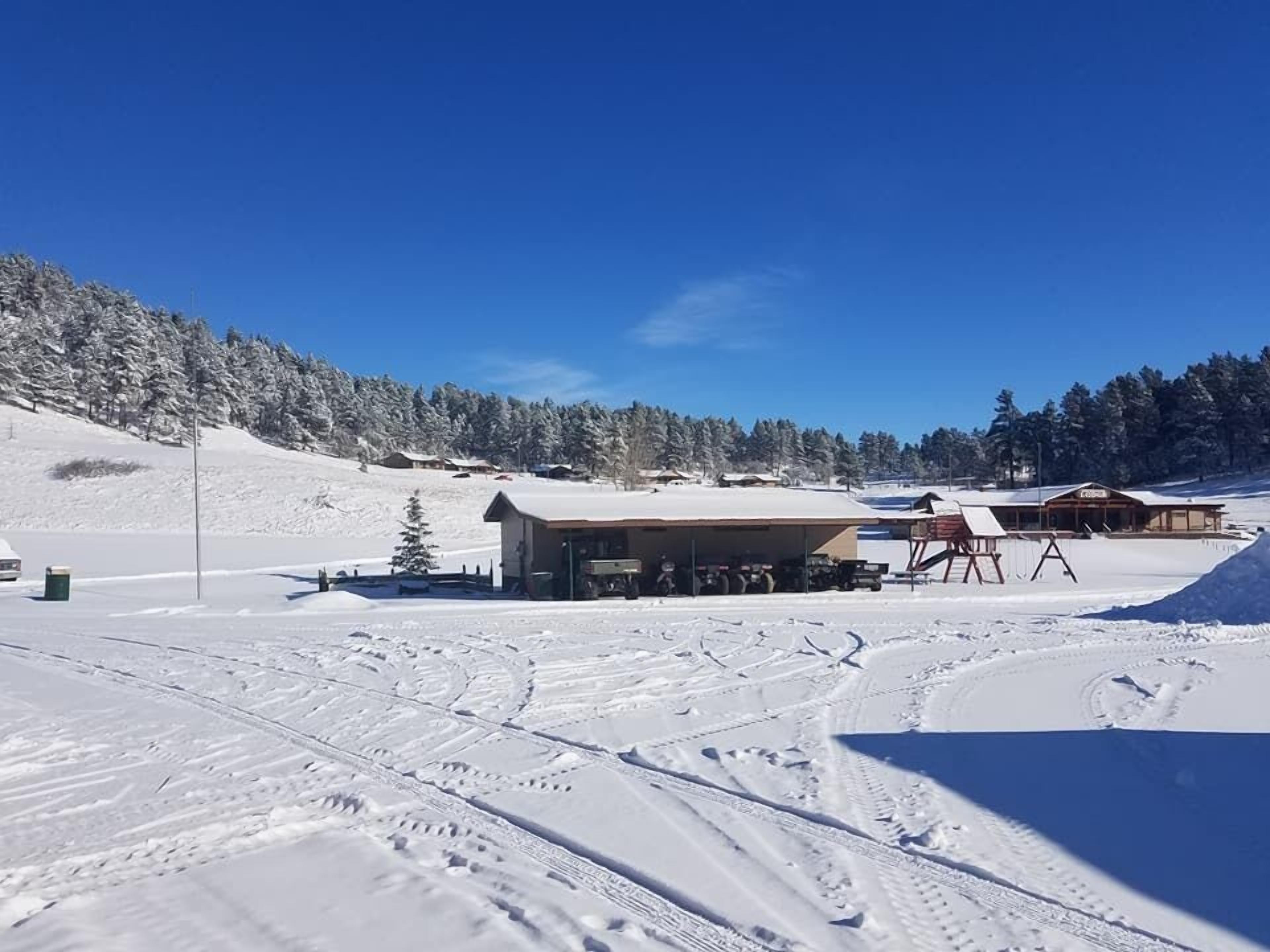 A snow-covered ski resort with buildings, ski lifts, and tracks.
