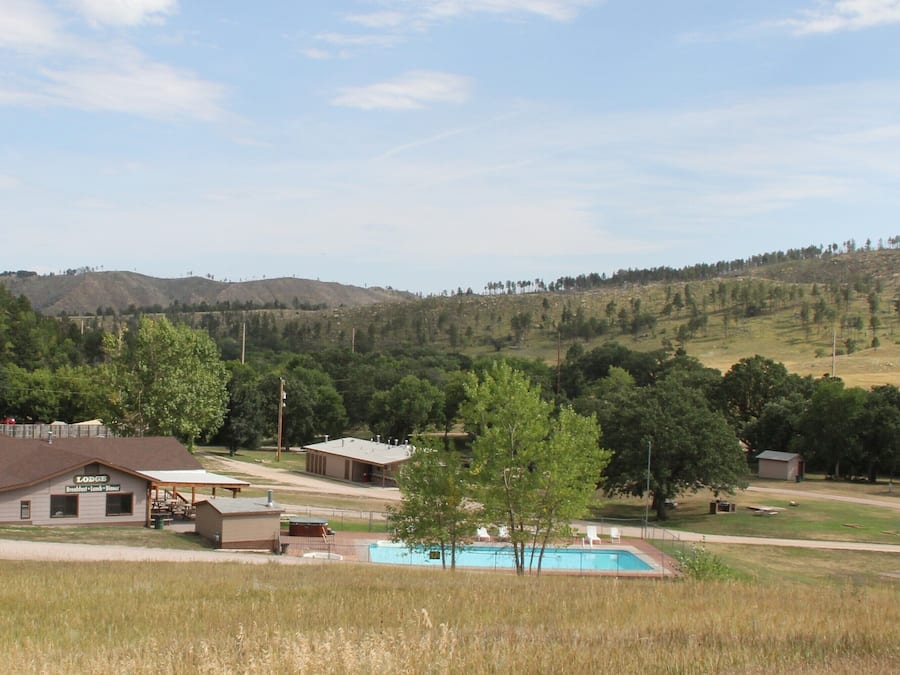 Un chalet doté d’une piscine, entouré d’un paysage vallonné et de nombreux arbres.