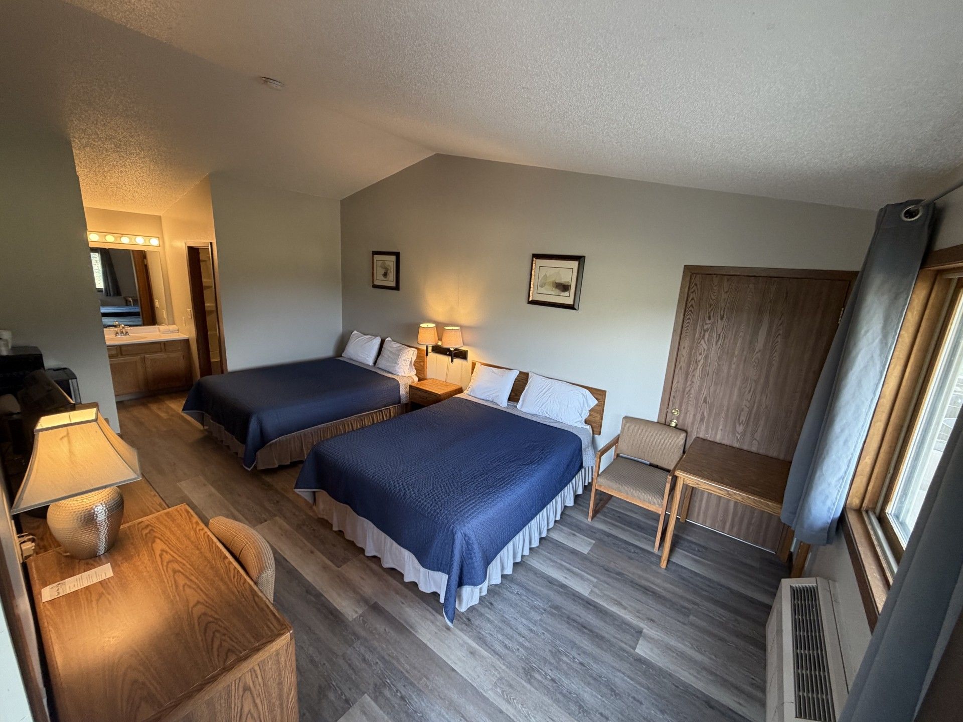 Une chambre d’hôtel avec deux lits, un bureau, une chaise et une fenêtre.
