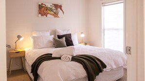 A neatly made bed with white bedding, a green throw blanket, and a pillow. There are two bedside lamps on wooden nightstands. - Moyne Views 2 - Overlooking The Edge Of The Moyne River (Port Fairy)
