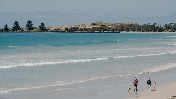 A beach with a clear view of the ocean, a sandy shore, and a distant hill with trees. - Moyne Views 2 - Overlooking The Edge Of The Moyne River (Port Fairy)