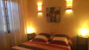 A bedroom with a bed, two bedside lamps, a wall clock, and a painting. - Sunny A/C apartment with terrace overlooking countryside and private pool (Saint-Pargoire)