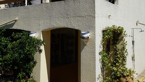 A two-story building with a balcony, a potted plant, and a hose on the ground. - Sunny A/C apartment with terrace overlooking countryside and private pool (Saint-Pargoire)
