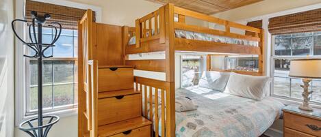 A bunk bed with a wooden ladder, a small table, and a chair with a metal frame.