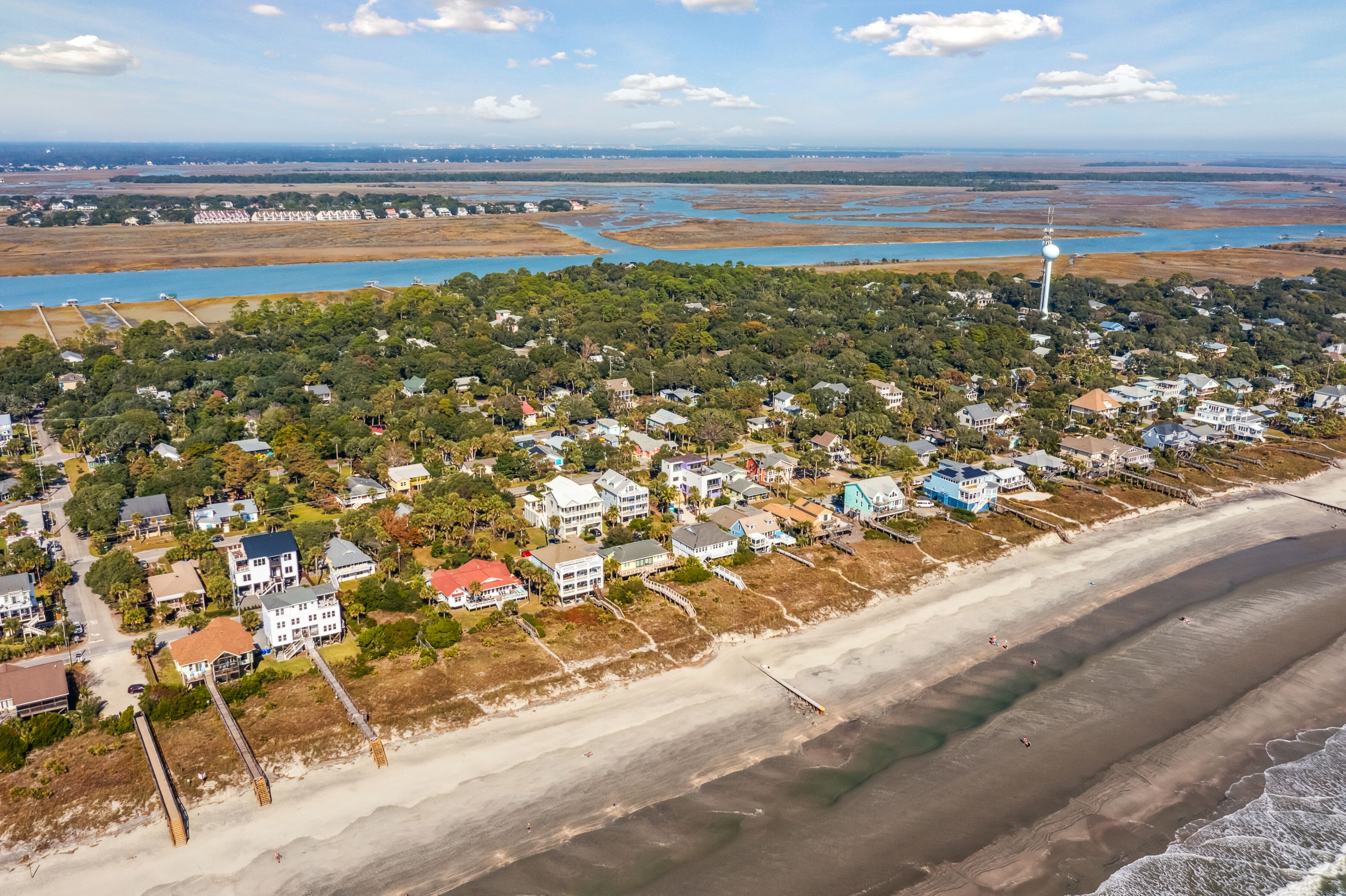 An aerial view of a coastal town with houses, a beach, and a lighthouse.