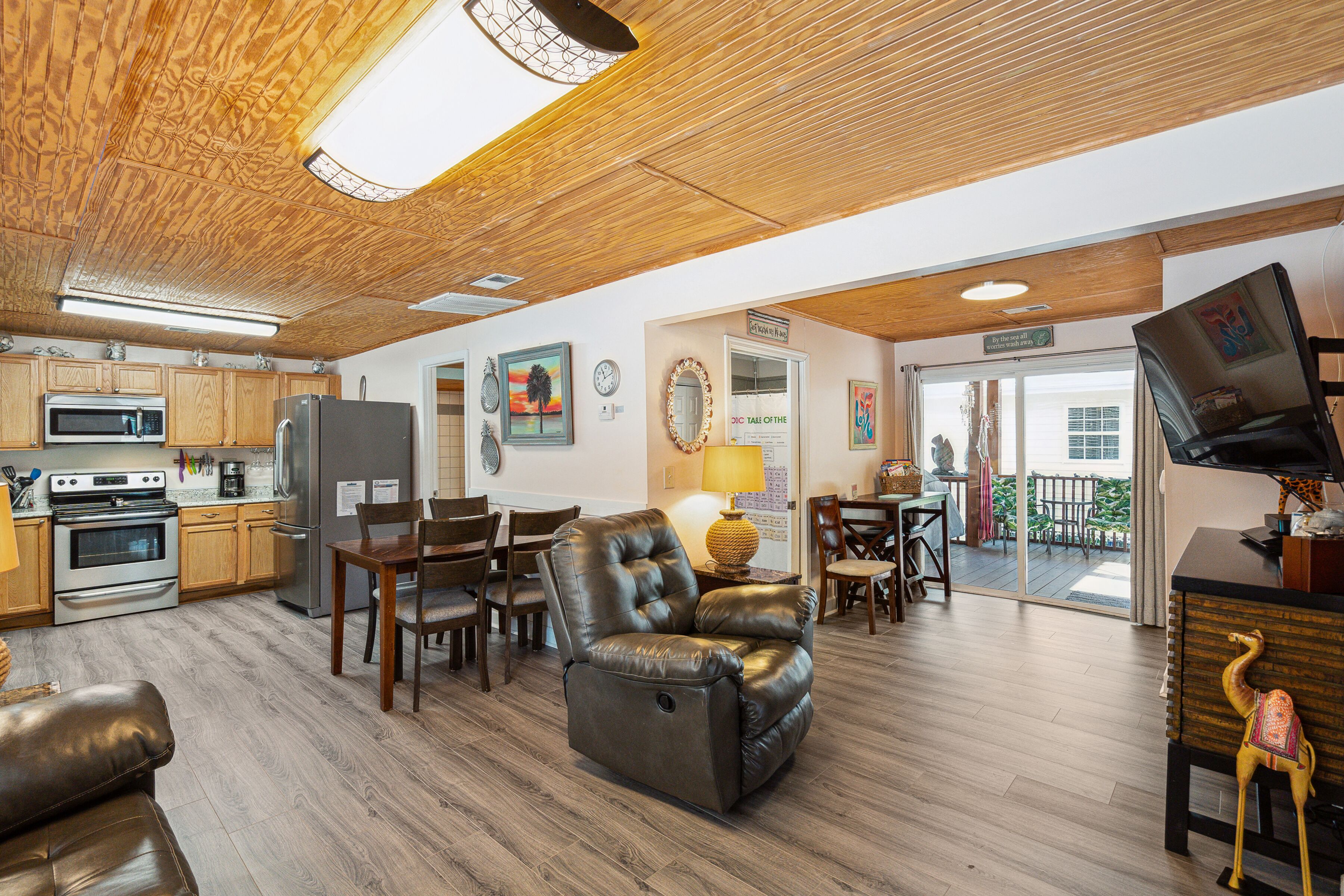 A spacious living area with a dining table, leather recliner, and a kitchen with modern appliances.