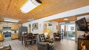 Ein geräumiges Wohnzimmer mit Esstisch, Ledersessel und einer Küche mit modernen Geräten.