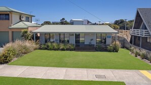 A modern house with a flat roof, large windows, and a well-maintained lawn. - Ocean Spray Retreat - sitting just block from the Southern Ocean (Port Fairy)