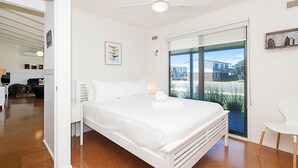 A modern bedroom with a large bed, a desk, and a view of the outside. - Ocean Spray Retreat - sitting just block from the Southern Ocean (Port Fairy)