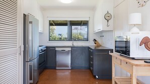 A compact kitchen with a dishwasher, stove, and microwave. - Ocean Spray Retreat - sitting just block from the Southern Ocean (Port Fairy)