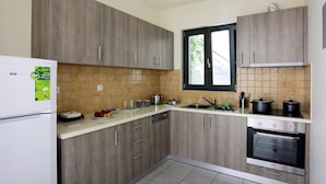 A modern kitchen with wooden cabinets, a built-in oven, and a window. - Ithaca's Poem (Ithaki)