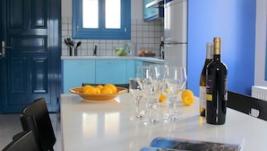 A kitchen with blue cabinets, a white countertop, a bowl of lemons, wine glasses, and a bottle of wine. - Ithaca's Poem (Ithaki)