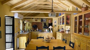 Una cocina con una mesa y sillas de madera, una lámpara colgante y armarios con puertas de vidrio.