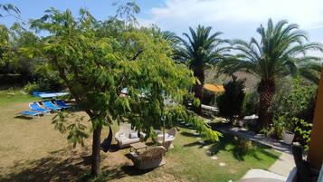 An outdoor area with lounge chairs, a small table, and a tree.