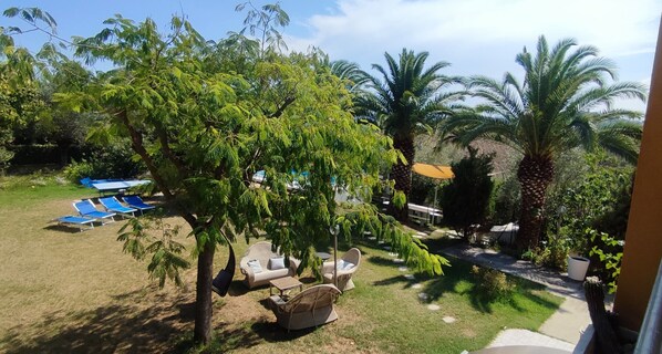 An outdoor area with lounge chairs, a small table, and a tree.