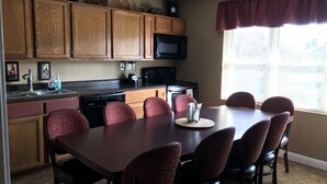 Une cuisine dotée de meubles en bois, d’un four à micro-ondes, d’un évier et d’un coin repas avec une table et des chaises.
