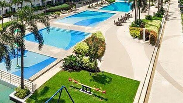 A modern hotel with multiple high-rise buildings, a central swimming pool, and well-maintained landscaping.